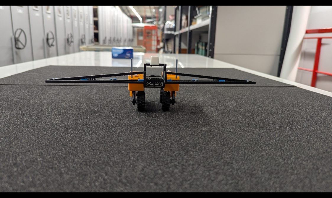 3D printed model of a yellow robot featuring little wheels and a black wiper at the front