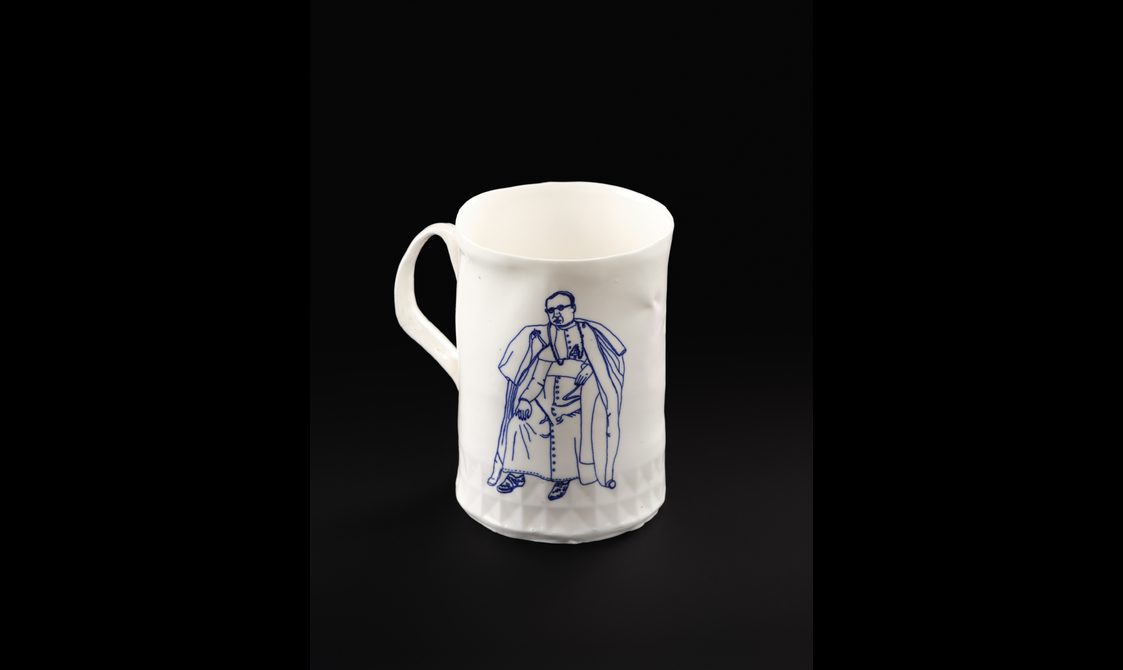 White bone china mug with extruded handle showing illustration in blue of a clergyman wearing glasses
