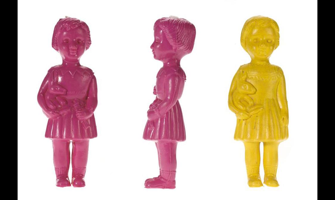 Two pink and one yellow doll in the shape of a little girl holding a toy.