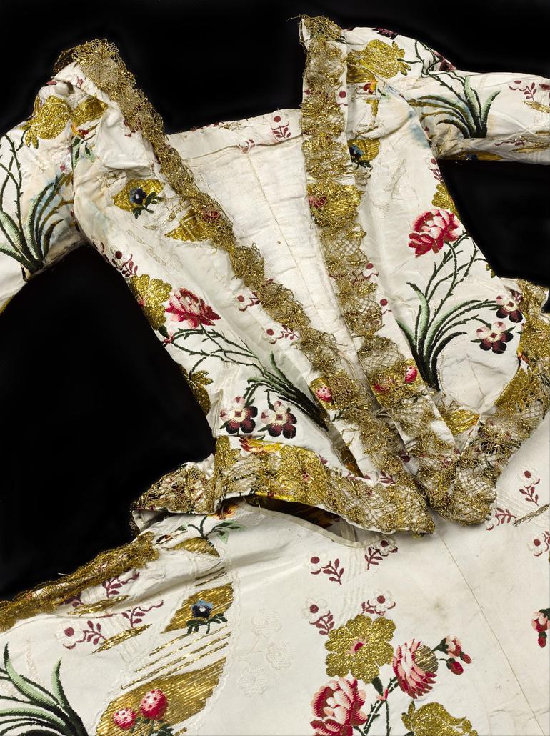 The bodice of an extravagant gown with complex pattern designs and gold brocade..