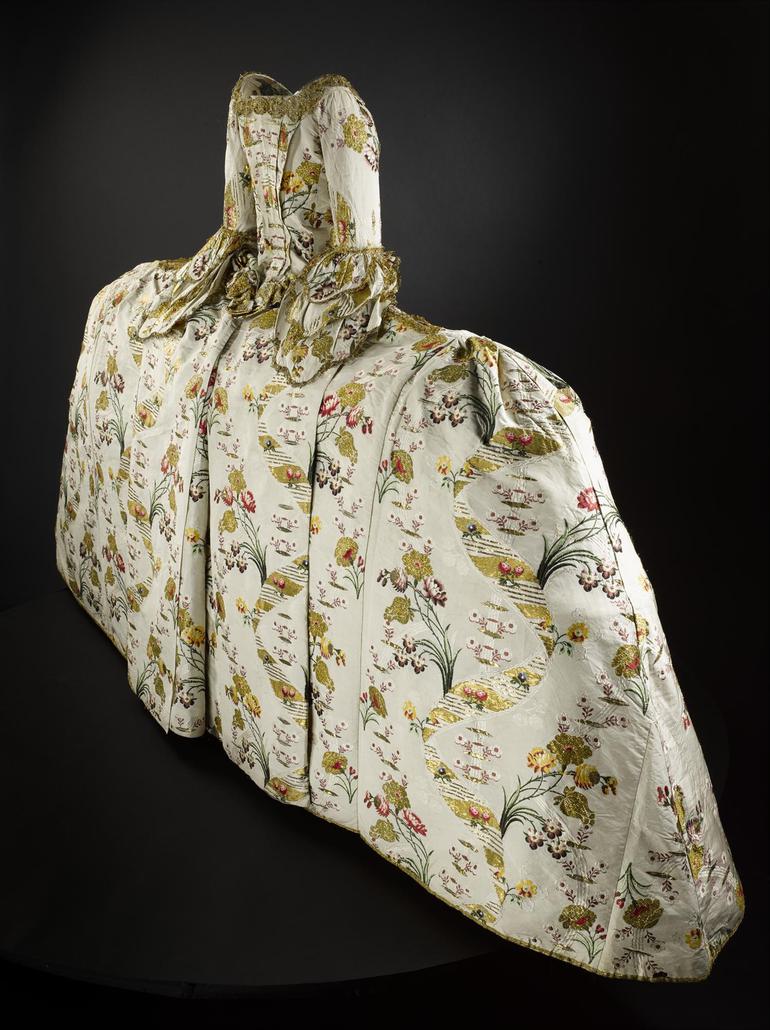 Side view of an extravagant gown with a wide skirt and complex pattern designs.