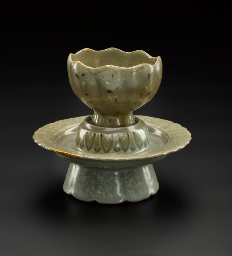 A light green-brown stoneware cup and stand shaped like a lotus flower.