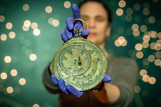 A woman holds an 11th century astronomical instrument known as an astrolabe.