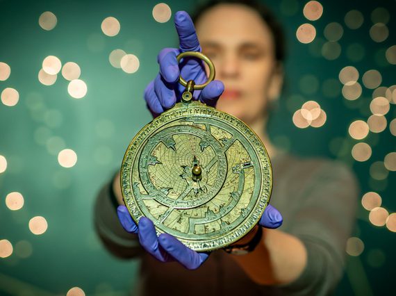 A woman holds an 11th century astronomical instrument known as an astrolabe.