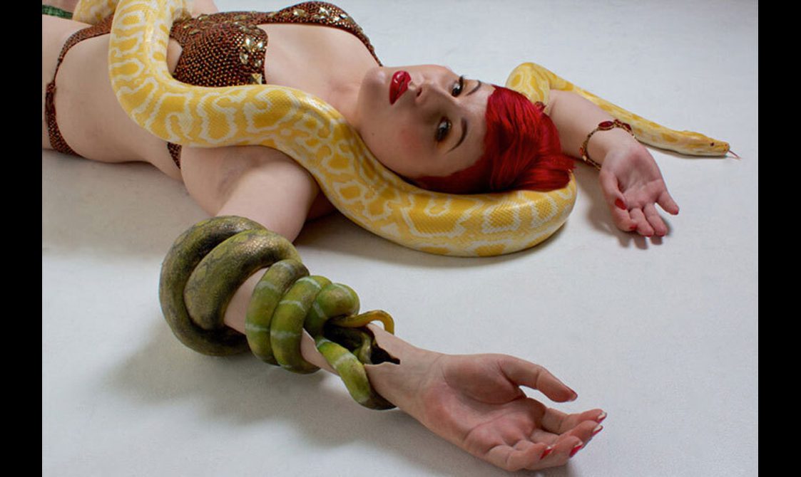 A model wearing a prosthetic arm designed like a green snake.
