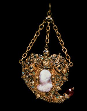 An ornate gold pendant in a heart-like shape featuring a white cameo of a woman's head and shoulders shown side on. The pendant hangs from three gold chains.