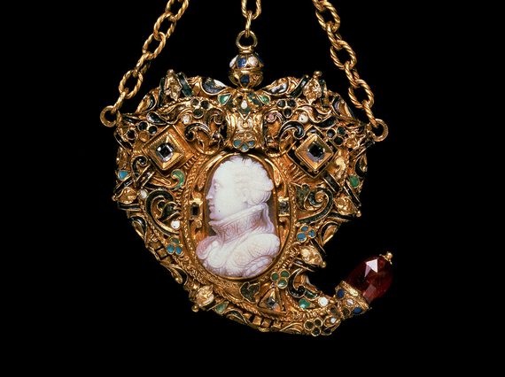 An ornate gold pendant in a heart-like shape featuring a white cameo of a woman's head and shoulders shown side on. The pendant hangs from three gold chains.