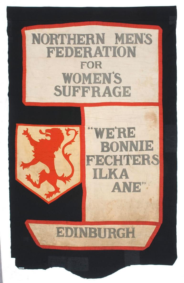 A banner with slogans and a red lion. The slogans read, "Northern Men's Federation for Women's Suffrage. We're bonnie fechters ilka ane. Edinburgh."