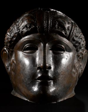 A bronze Roman face mask of a young female face.