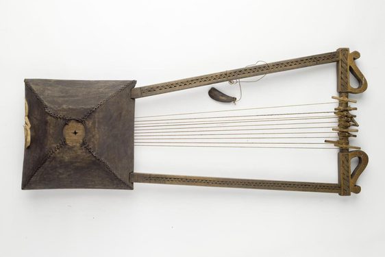 Wooden trapezoid prism shaped box with three U shaped wooden sticks attached horizontally to the box. Numerous thread strings attached between the box and the vertical stick.