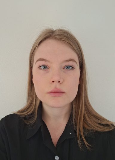 A woman with brown hair is looking directly at the camera.