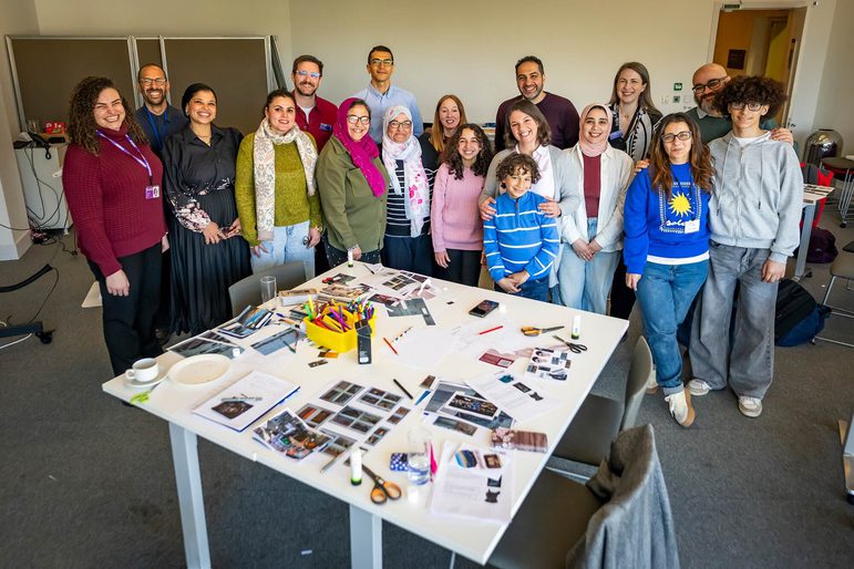 A large group of people standing around a craft table, smiling for a photo.