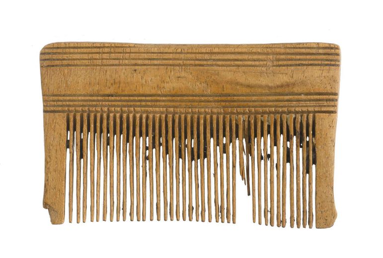 A small wooden lice comb with thirty-nine teeth. Some of the teeth have broken off.