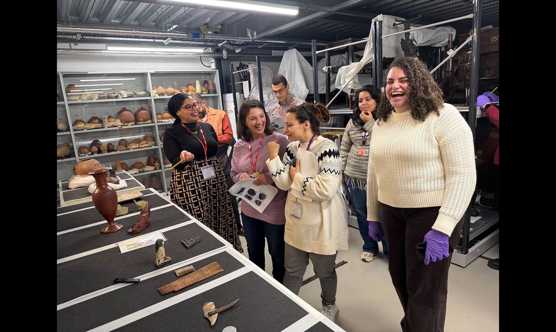 A group of visitors looking at Egyptian objects in a museum store.