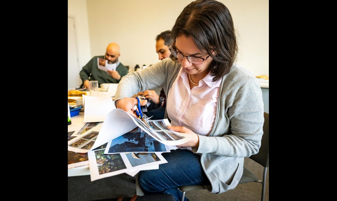 A woman cutting out pictures from a piece of paper.