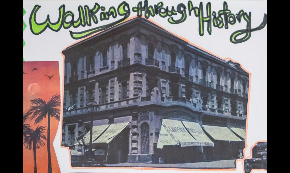 A zine from the Egyptian heritage workshop with a collage of images representing Egypt. The central image is a corner building with several windows. The ground floor of the building is a shop with awnings at the entrances. The top of the zine reads 'Walking through history'.