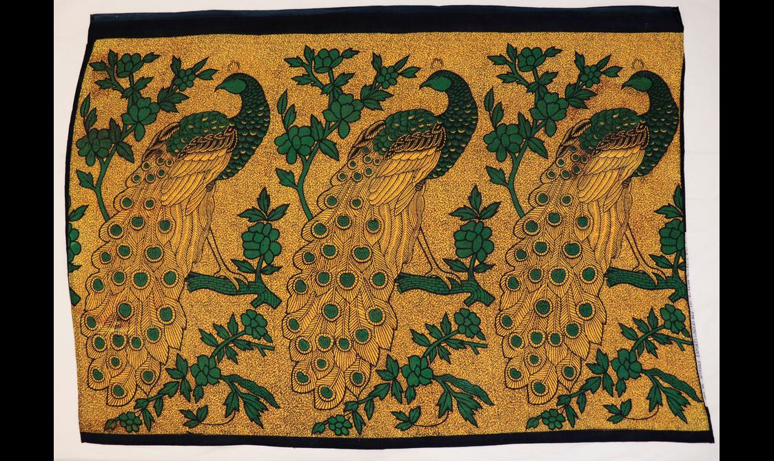 Gold textile with pattern of large black and green peacocks perched on branches.