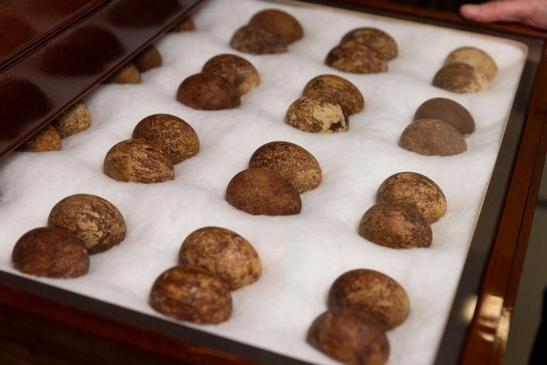 An open wooden drawer displaying pairs of brown eggs in rows.