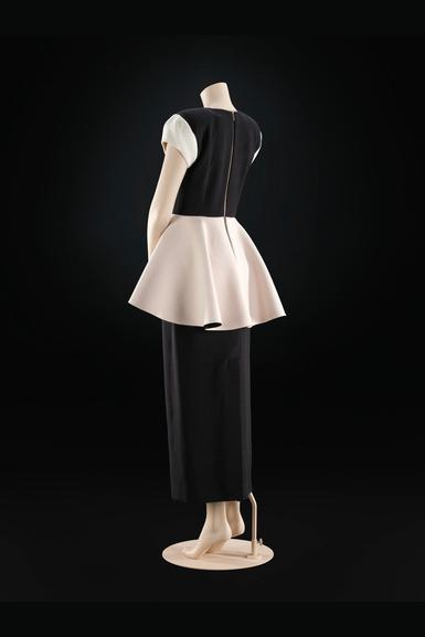 A mannequin wearing a black dress with a white peplum