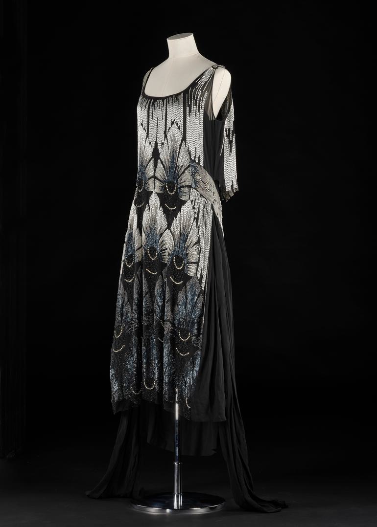 A dress model wearing a black dress with silver beading