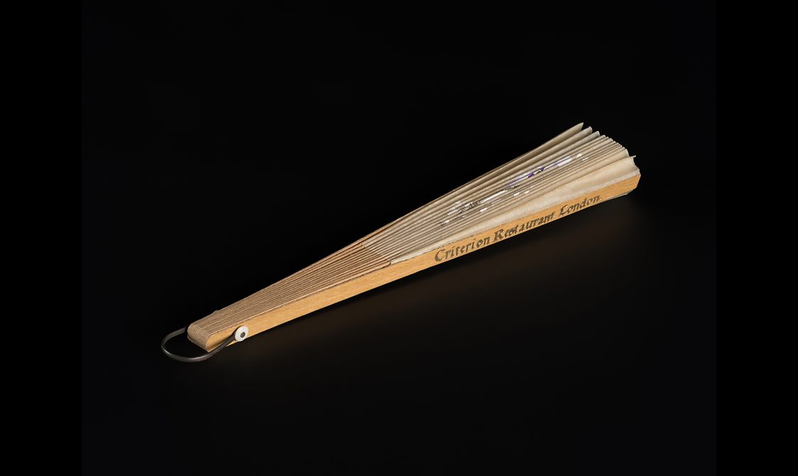 Folded decorative fan. 'Criterion restaurant London' printed across the wooden guard in gold leaf.