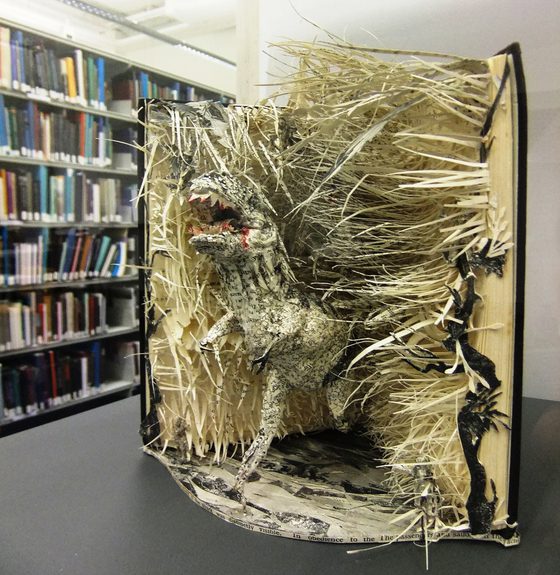 An open library book with the pages cut into the shape of a t-rex.