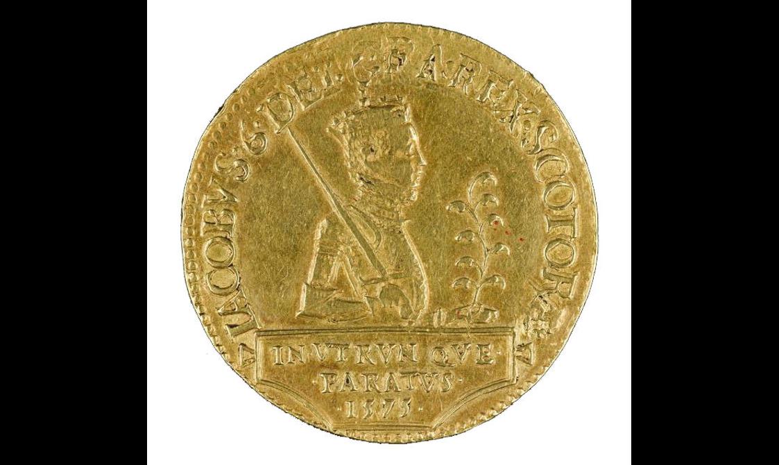 A gold coin with a king in profile and letters around the edge.