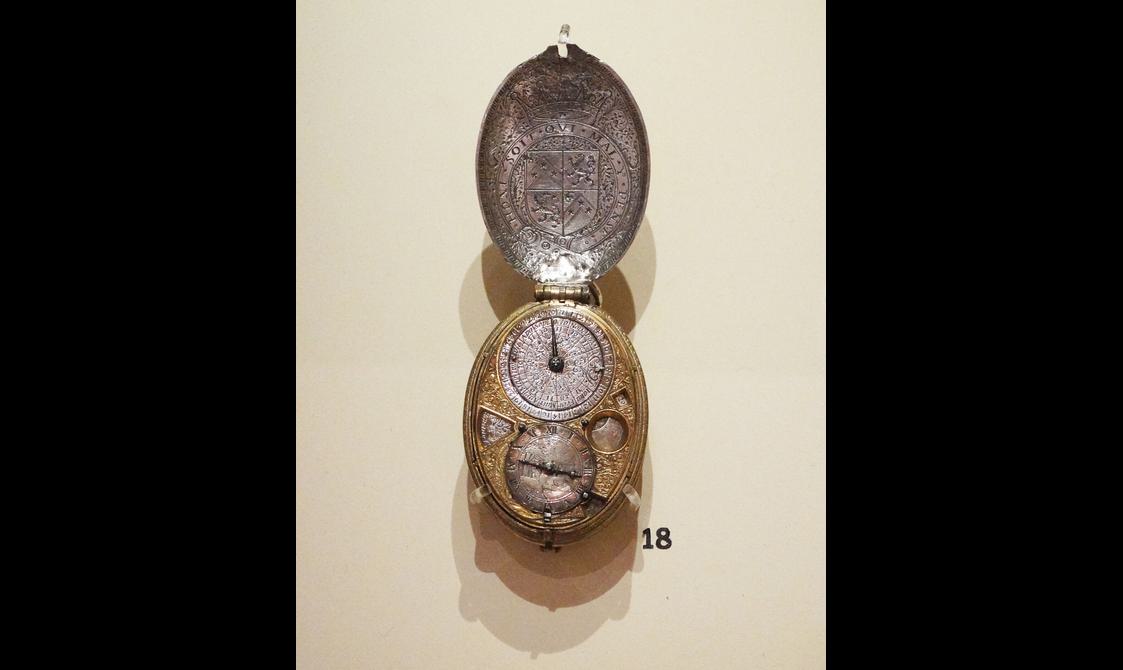 An elaborate silver and gold pocket watch with a royal crest and two dials.