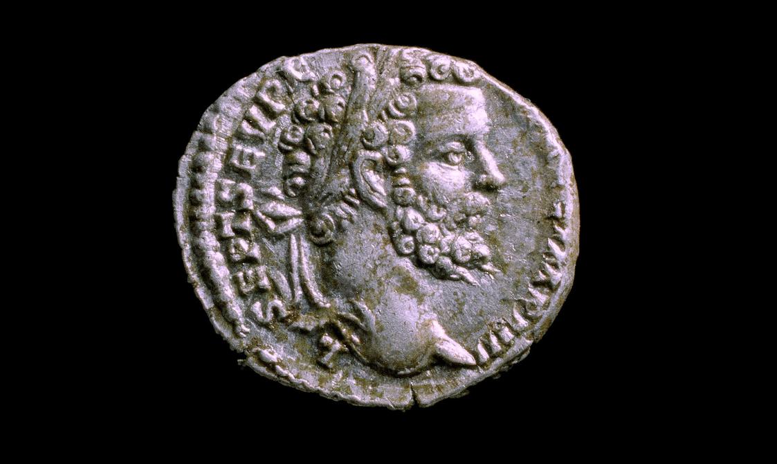 Silver coin, warped at the top depicting a heavily bearded man in profile.