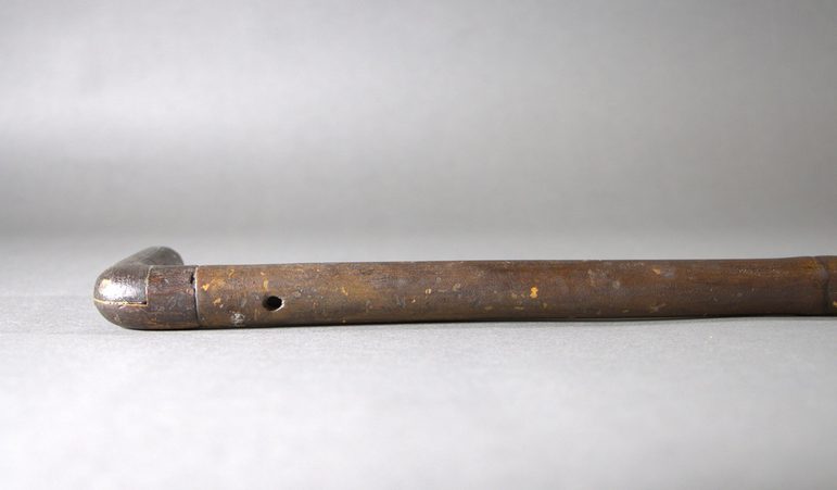 A close up of the top end of a poacher's fishing stick. There is clearly a very small round hole in the top end, near the handle.