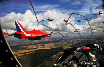 The view from the cockpit of a red arrow aircraft with a view of other red arrow aircrafts flying