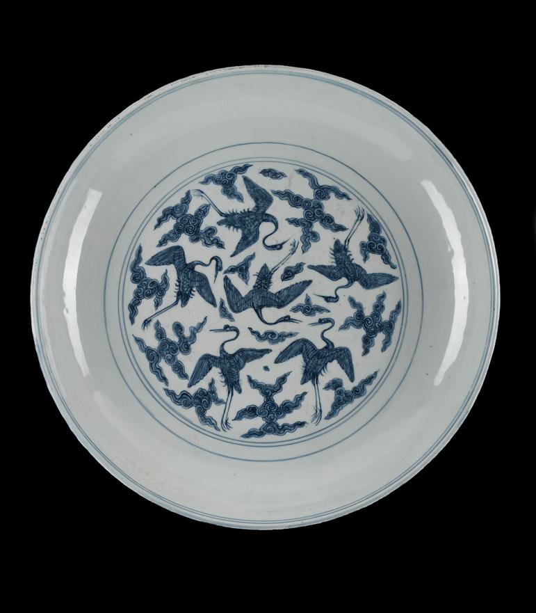A circular white dish with painted blue crane birds in the centre.