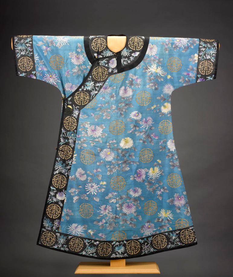 A blue Chinese robe with floral details and a decorative black trim hanging on a stand
