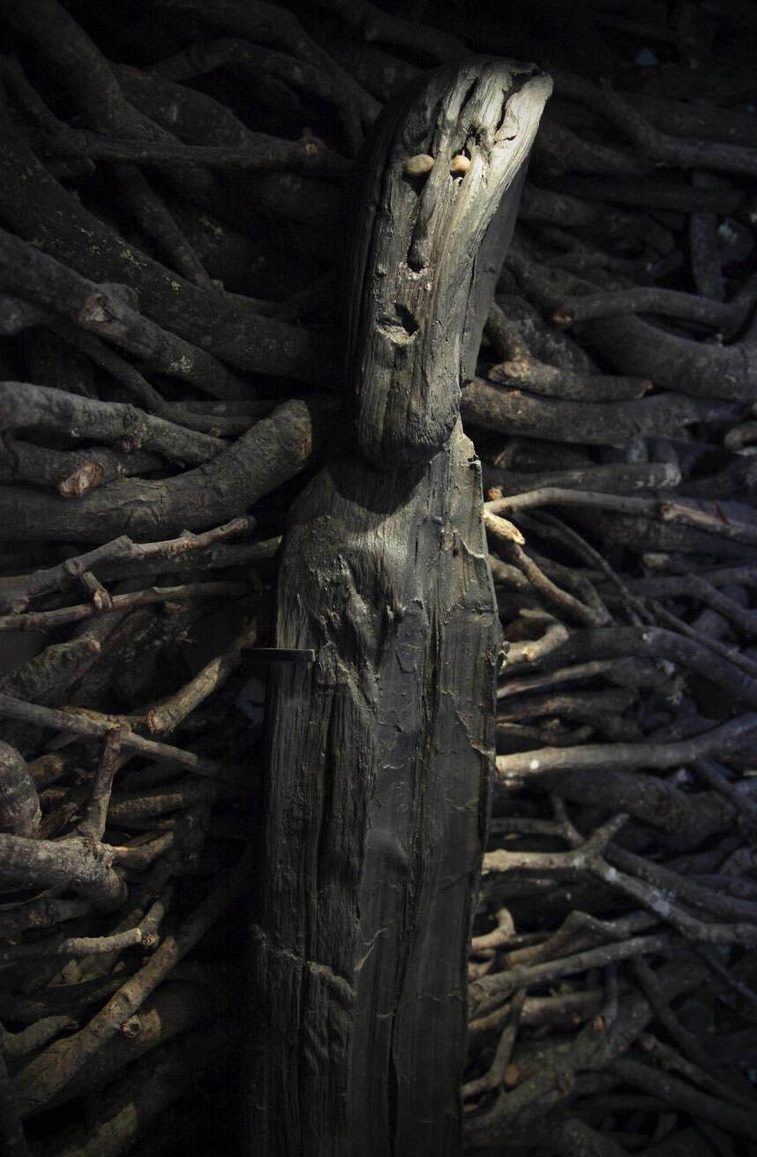Iron age sculpture made from alder wood with quartzite pebbles for eyes.