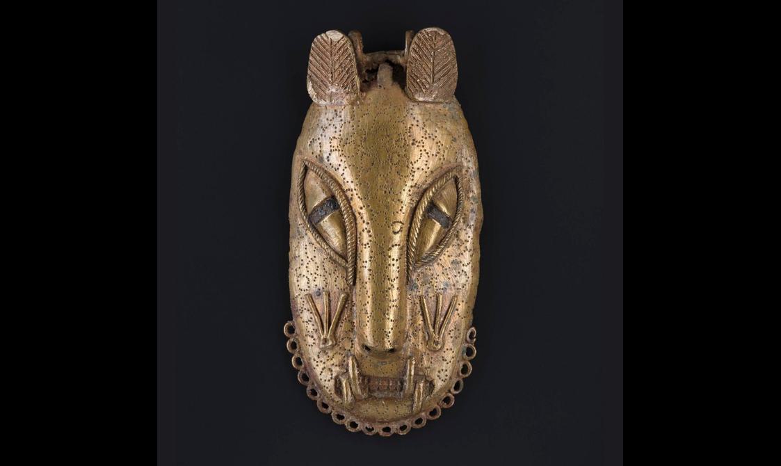 A brass mask of a stylised leopard face