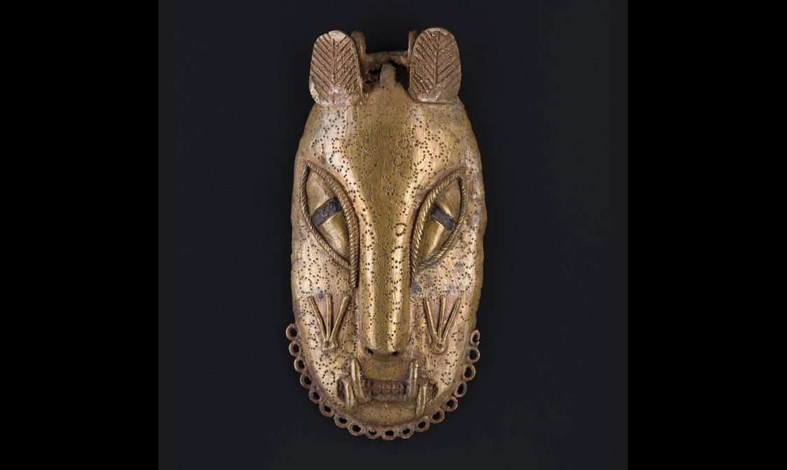 A brass mask of a stylised leopard face