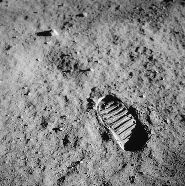 A thick boot print on grey sand-like ground