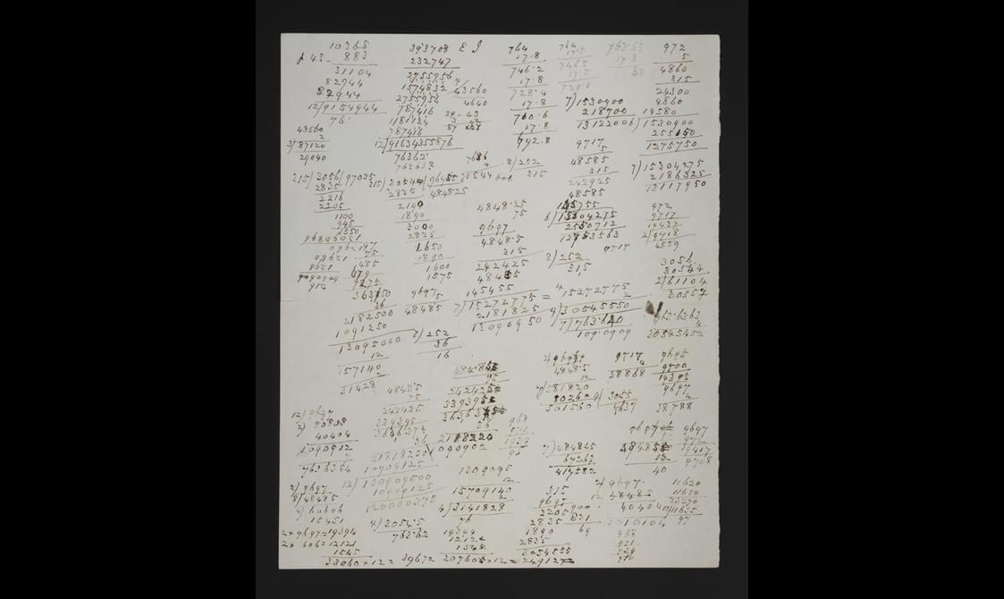 A sheet of paper with lots of handwritten calculations drawn all over it in black ink