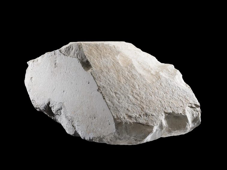 A large light coloured rock on a black background