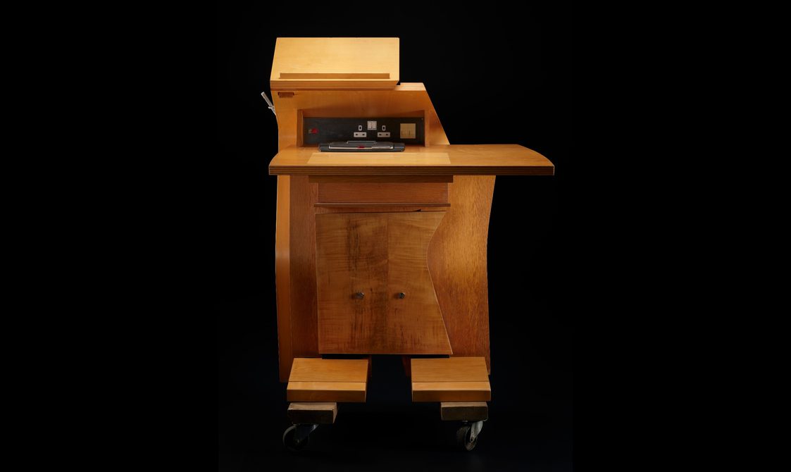 View of the desk from the user's perspective. The curves are flattened, with the focus on several power outlets built into the upper desk.