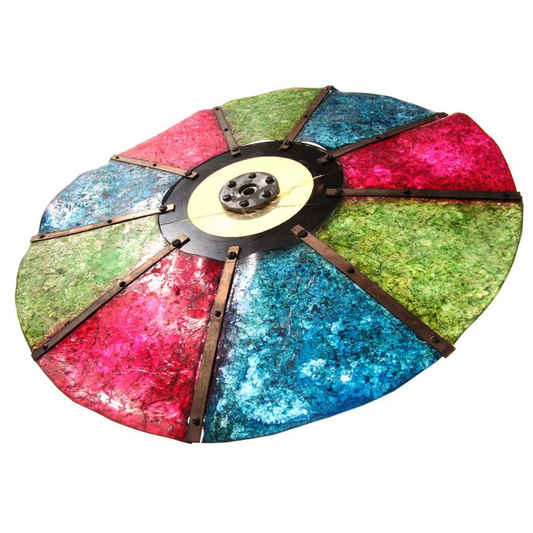 A colour photograph of a circular disc made up of red, blue and green semi-opaque panes against a white background. There are 2 of each colour alternating and connected by a central solid hub.