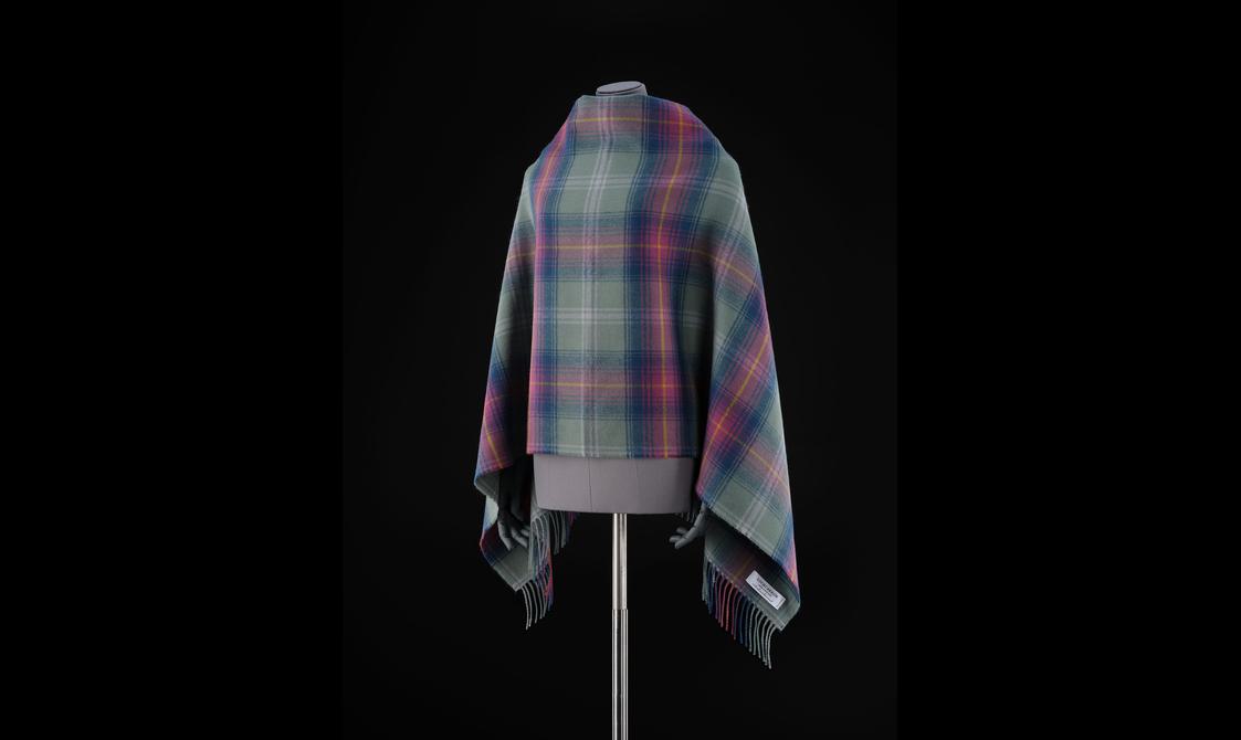 A mannequin wearing a purple, pink, and green tartan shawl.