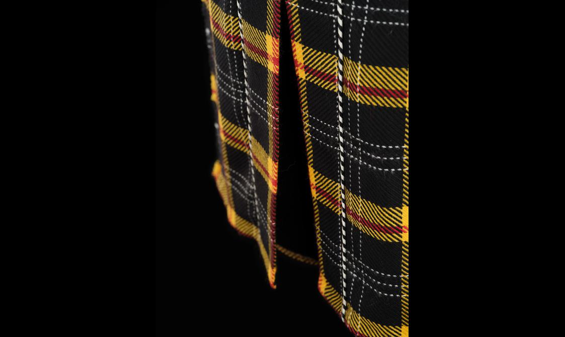 A detail of a yellow and black tartan kilt