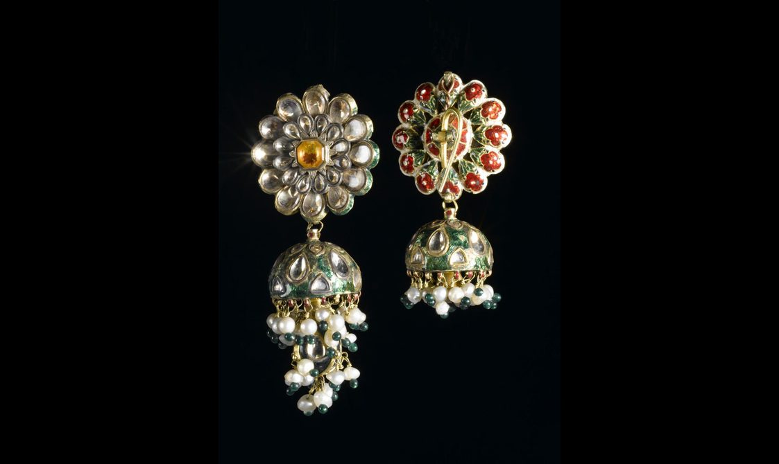 Decorative earrings with a floral design at the top and a dangling attachment with white and green beads.