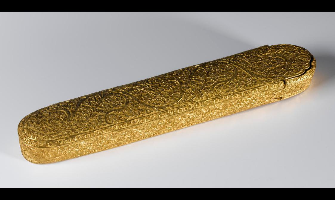 A long pen case made of gold with intricate patterns all over its surface