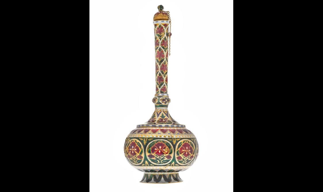 A detail of a round bottle highly decorated with red, gold, green, and white patterns