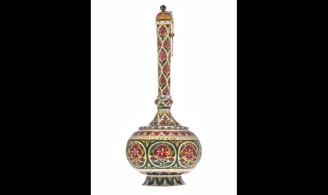 A detail of a round bottle highly decorated with red, gold, green, and white patterns