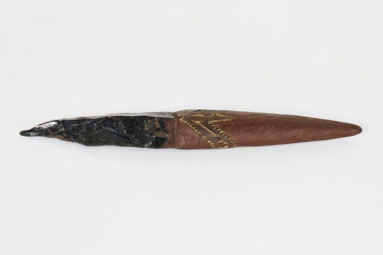 Knife with an obsidian blade and wooden handle covered with red painted gum, ornamented with incised bird designs.