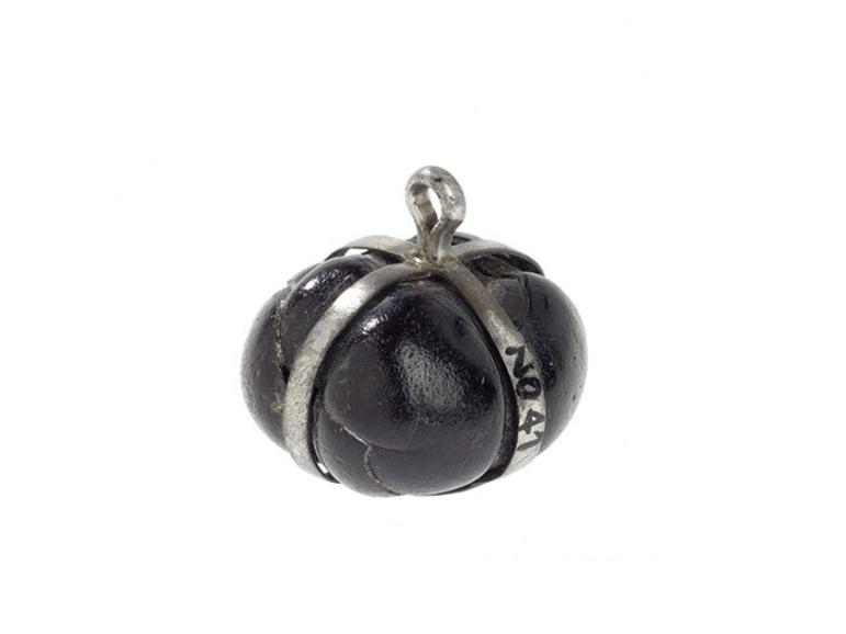 Dark brown seed mounted in silver bands. There is a small silver hoop for a chain at the top of the strips.