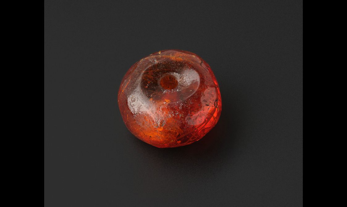 A small amber bead with a hole through the centre.